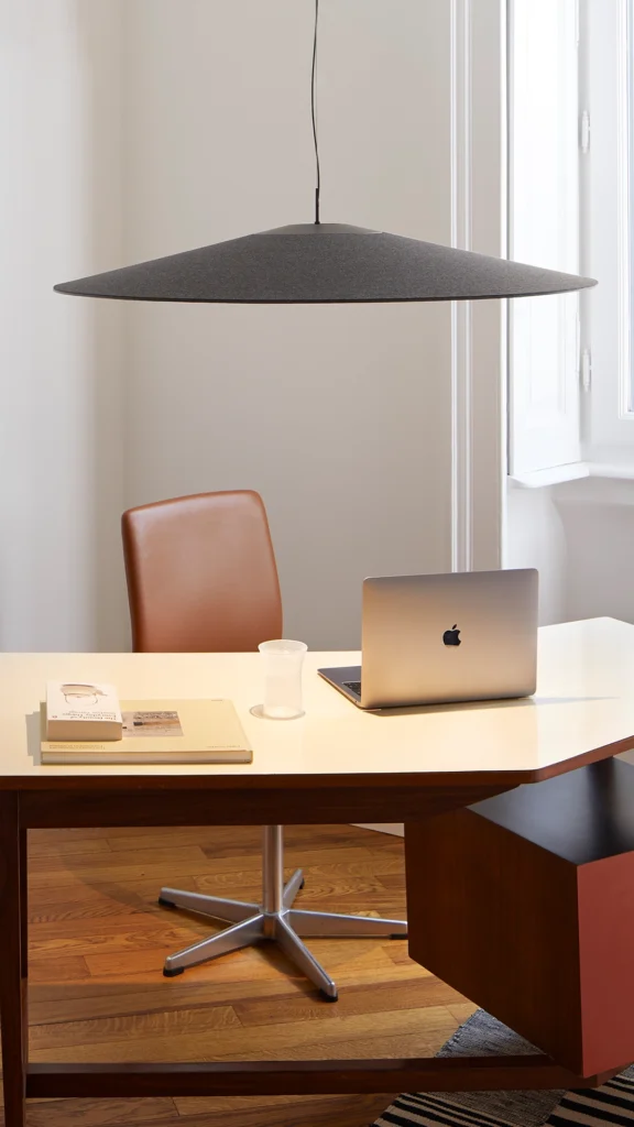 The suspension acoustic lamp Koinè is set in a home-office situation. The lamp has an outstanding lighting output